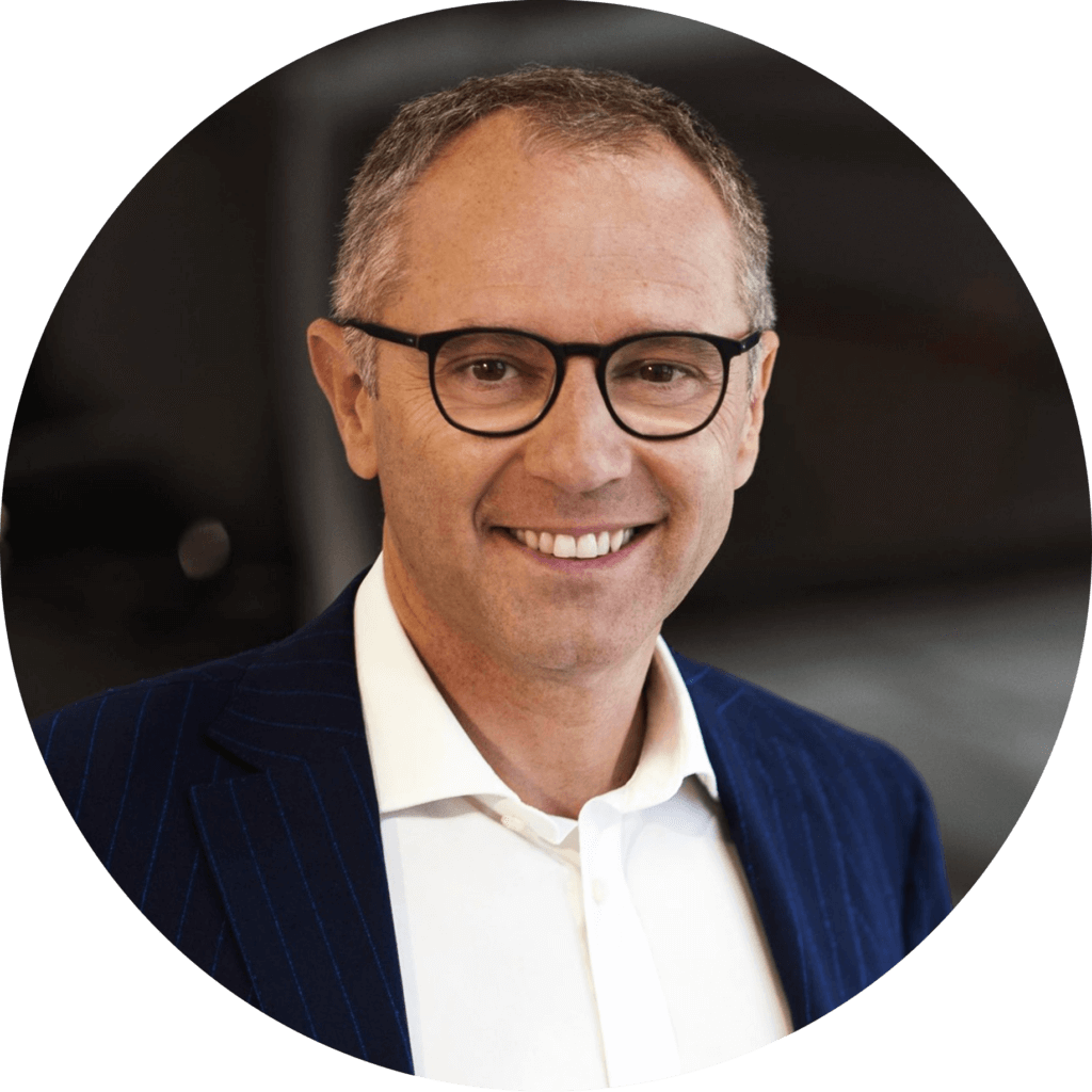 A headshot of Stefano Domenicali smiling directly to the camera as he is quoted speaking on the power of sustainability in sports
