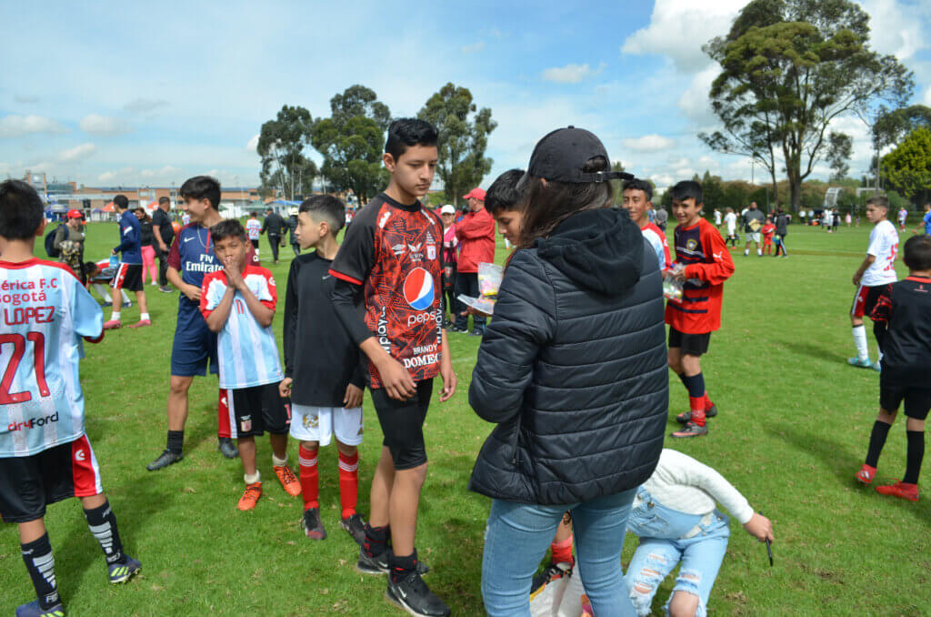 A large group of children in football clothes on a sports field, they look happy