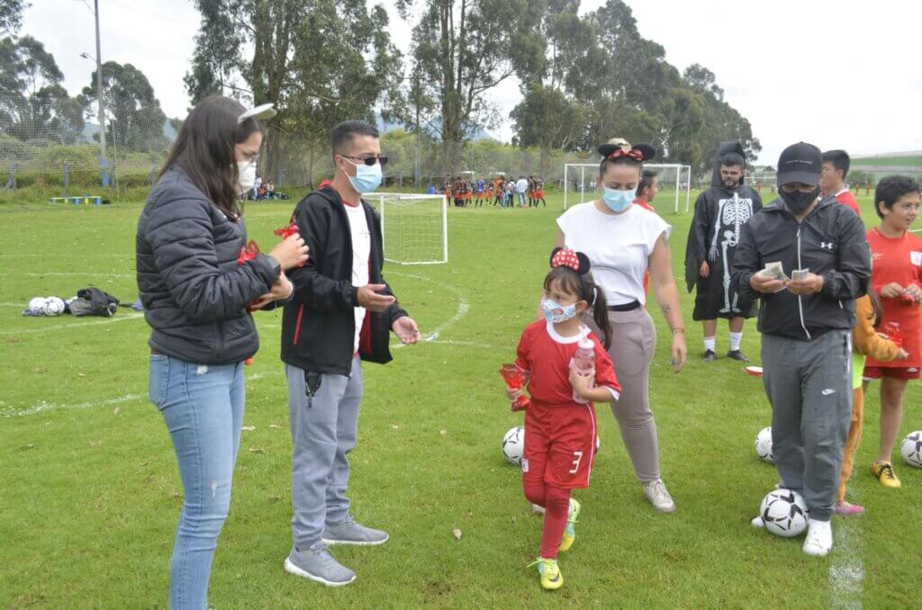 A group of people on a football field, some wearing masks, some Minnie mouse ears while others literally dressed up as death