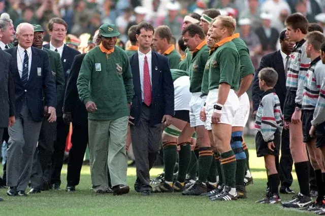 Nelson Mandela walks past Francois Pienaar in the line up before the Rugby World Cup Final in Johannesburg's Ellis Park. On the far left is Sir Ewart Bell Chairman of World Cup Rugby.