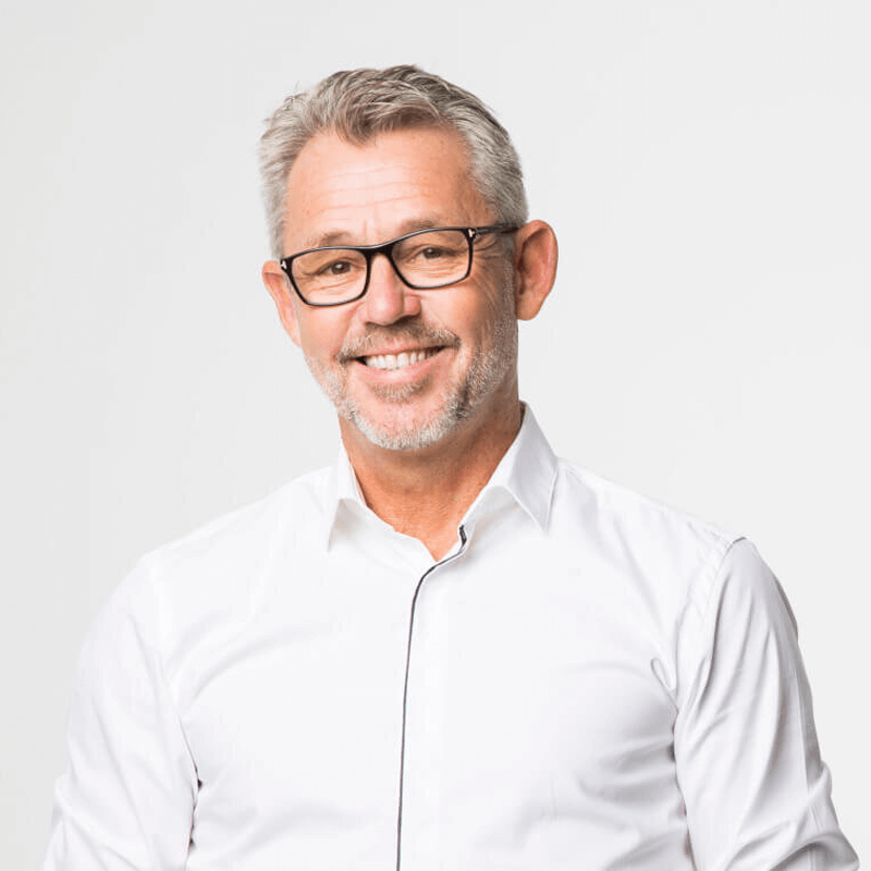 KLrister Bergström in a white shirt, wearing glasses, smiling, the background is white