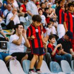 A child cheering at a game wearing his team jersey